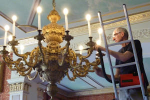 Terry Brotheridge working  a gilt wood chandelier at The Tabley House Collection