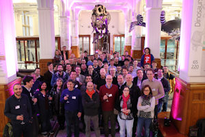Group gathered in Manchester Museum with T-Rex skeleton behind them. 