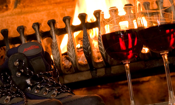 walking boots and wine glasses by an open fire