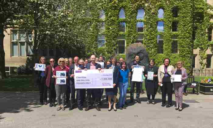 Group celebrating making a million with a giant cheque