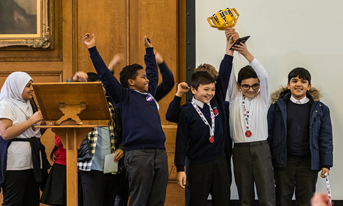 School children celebrate winning with a lego trophy