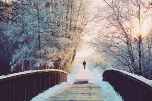 Man walking across a frosty bridge