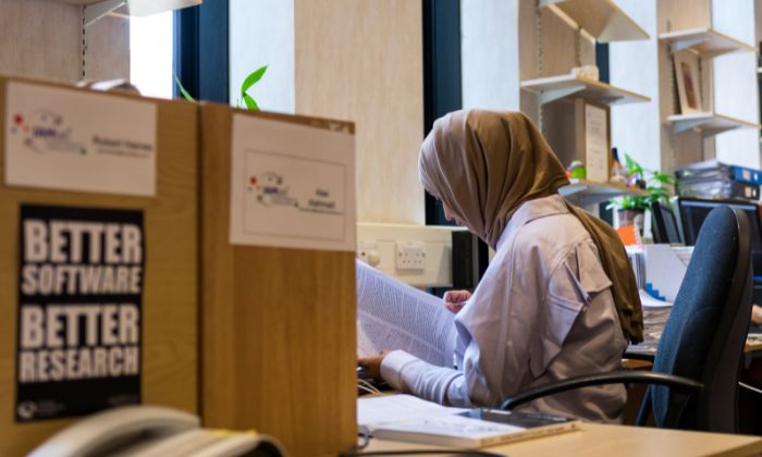 A researcher looking at a paper while sat at a desk in an office.