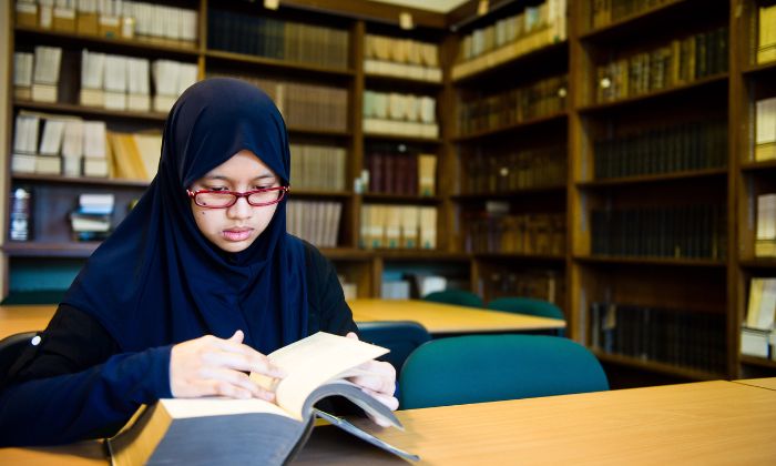 Student reading a book at a desk in Main Library