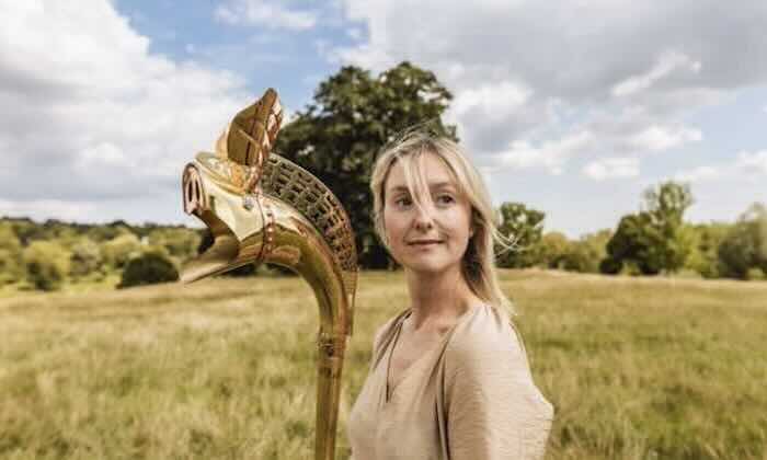 Archaeology PhD student Letty Stott in a field holding an instrument