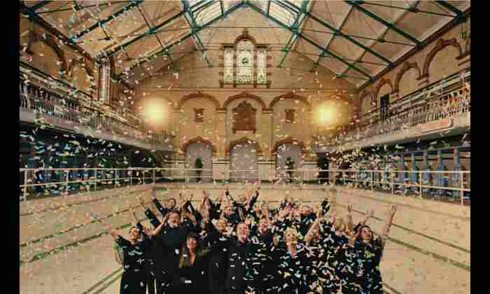 Image shows a group of people with arms in the air as confetti falls from above 