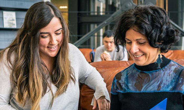Two researchers sat together looking at a laptop held by one