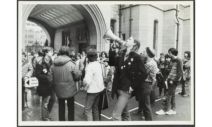 Student with a megaphone outside the University of Manchester arch on Oxford Roa