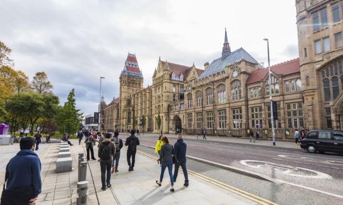 Students walking down Oxford Road past UoM buildings