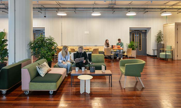 Students working and talking in a bright lounge area inside the Sister building 