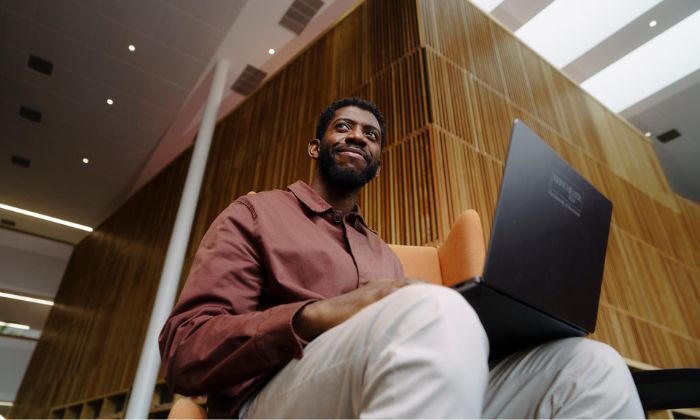 Man smiling into the distance whilst using a laptop