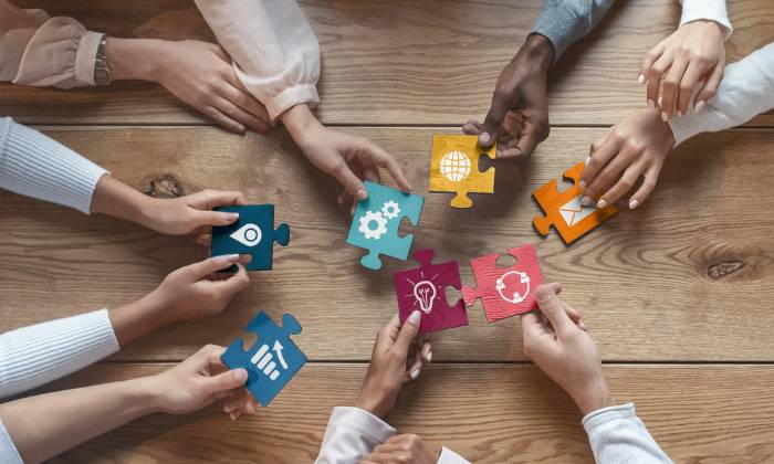 hands from above, holding out jigsaw pieces with symbols on for teamwork