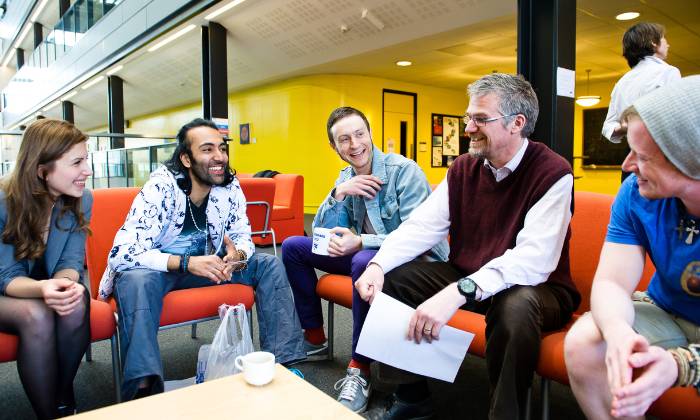 Colleagues chatting and smiling around a desk